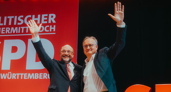 Der ehemalige SPD-Parteivorsitzende Martin Schulz und der Landesvorsitzende der SPD Baden-Württemberg Andreas Stoch stehen Arm in Arm auf einer Bühne nebeneinander und winken ins Publikum.